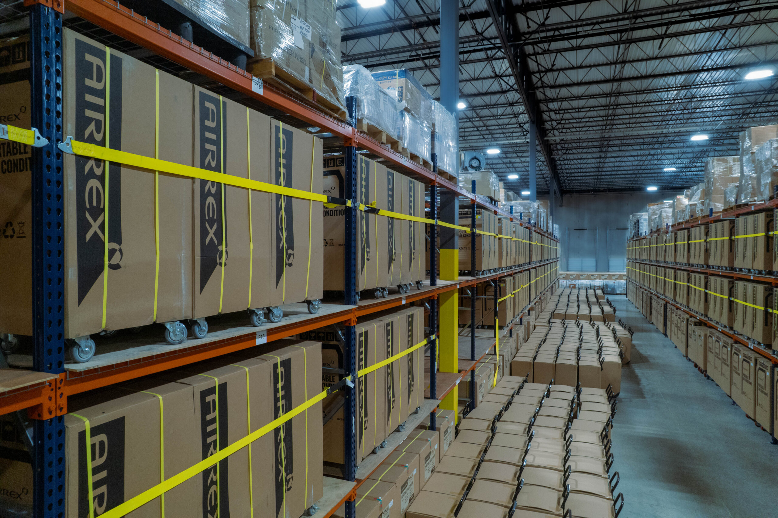 Large warehouse facility housing a massive rental fleet of Airrex portable climate control units on industrial shelving. This organized inventory management system by Temp-Air illustrates how strategic storage and maintenance of portable air conditioners optimize rental fleet ROI and ensure rapid deployment for industrial cooling needs.