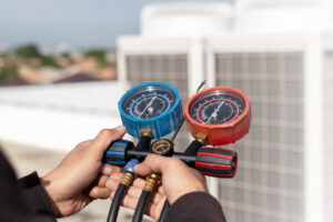 HVAC technician using refrigerant pressure gauges to service a rooftop air conditioning unit, illustrating the transition to R-454B refrigerant and HVAC system maintenance.